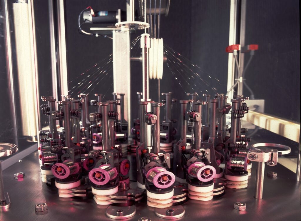 Automated machinery for precise, synchronized operations, featuring multiple colorful spindles and intricate mechanical components.