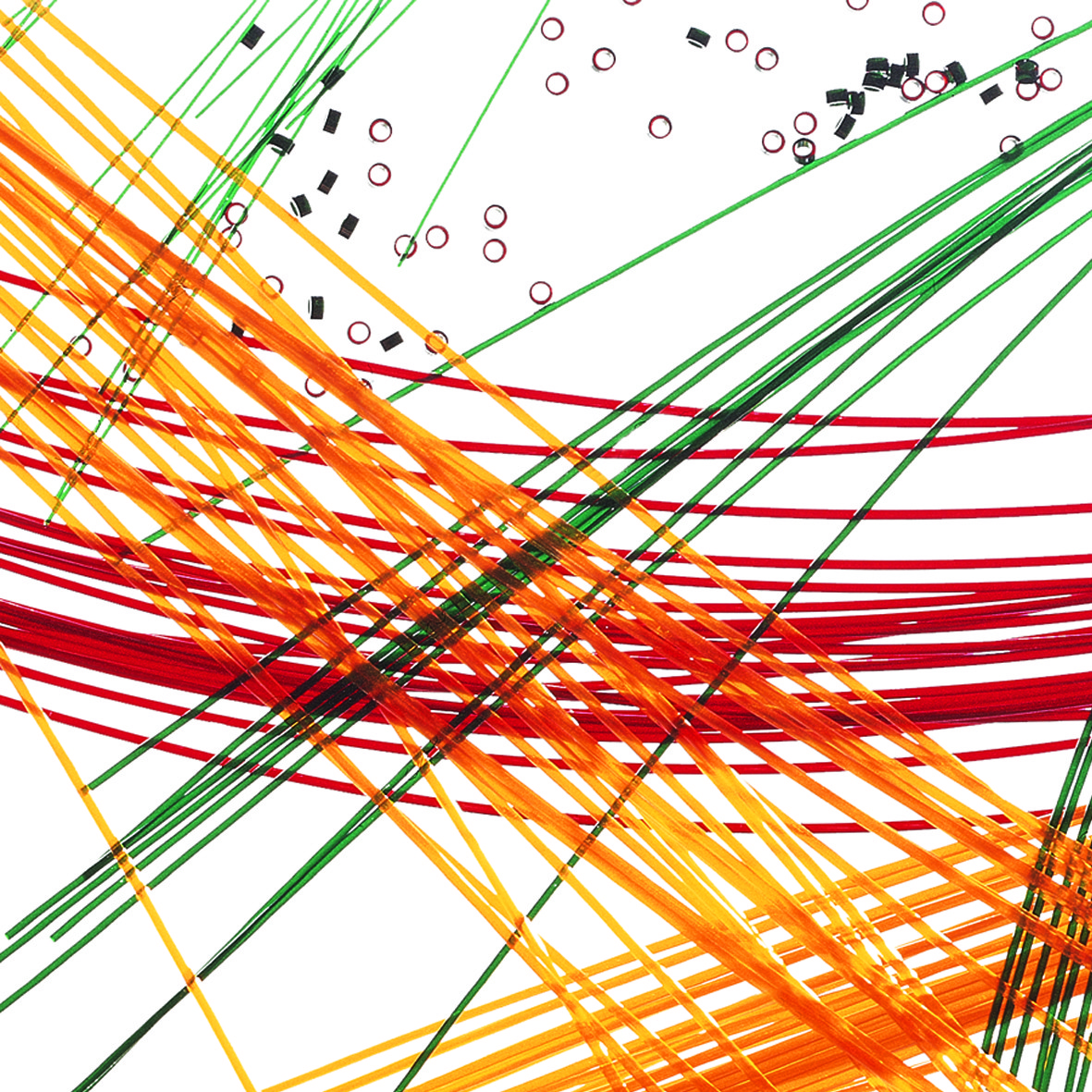 Colorful strands of orange, red, yellow, and green intersect on a white background, accompanied by small black and red circular objects, suggesting a dynamic art or craft project.