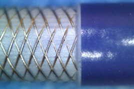 Close-up of a braided wire wrapped around a blue cylindrical object, illustrating a component used in electrical or mechanical applications.