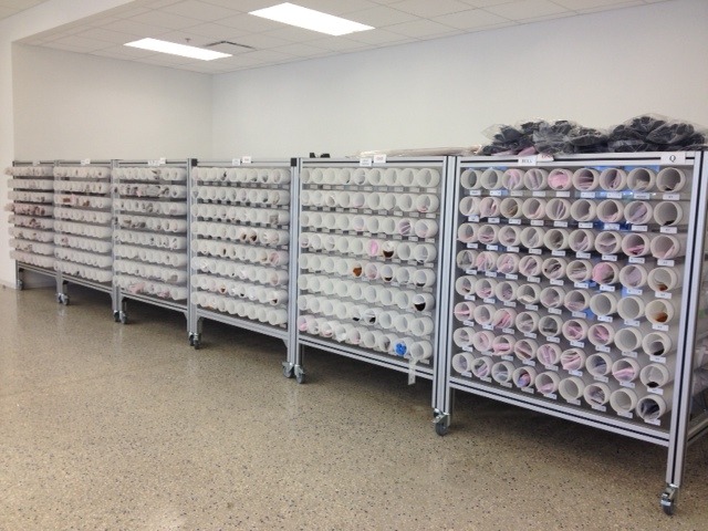 Shelves filled with cylindrical containers, organized in rows, showcasing various colors and materials, likely used for storage or inventory purposes.