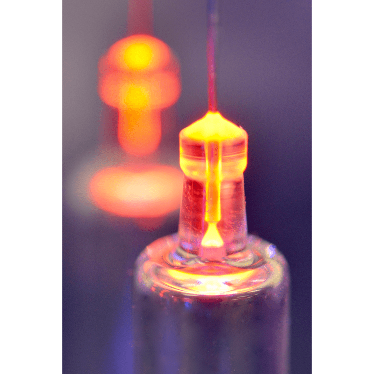 A glowing glass tube with a bright, orange plasma discharge visible at the top, illustrating a gas discharge experiment.