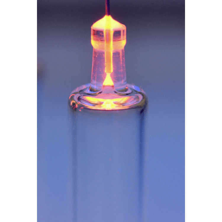 A glowing glass tube with a bright, orange plasma discharge visible at the top, illustrating a gas discharge experiment.