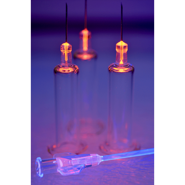 A glowing glass tube with a bright, orange plasma discharge visible at the top, illustrating a gas discharge experiment.