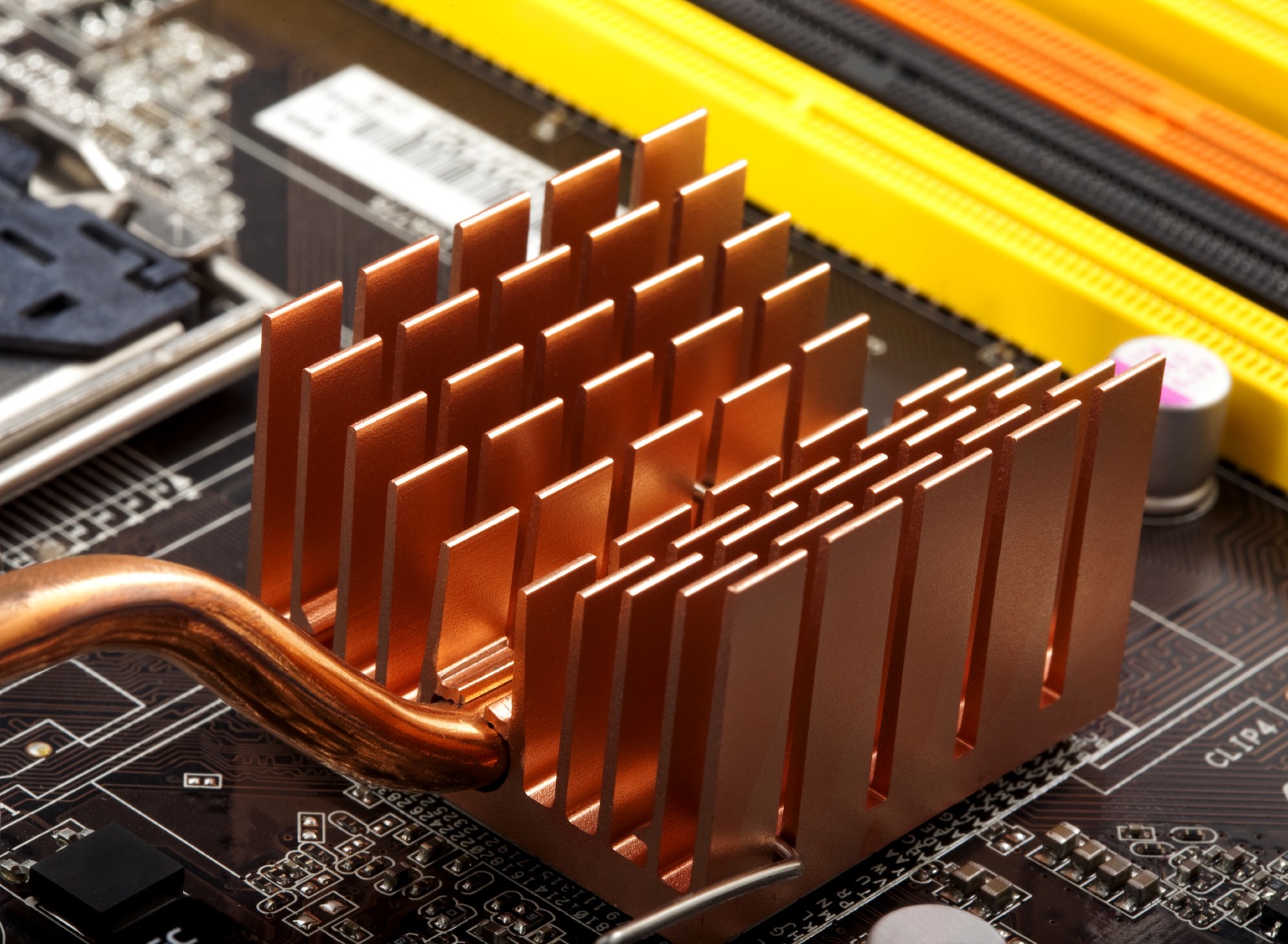 Copper heat sink with vertical fins on a motherboard, essential for cooling components during operation. Highlights thermal management in electronics.