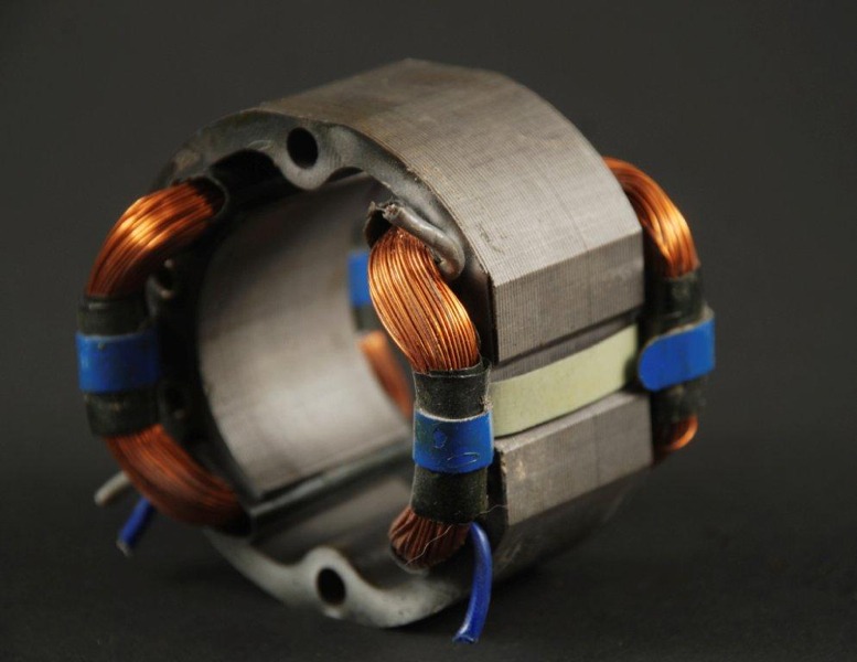 Close-up of an electric motor stator, featuring copper winding coils and a metallic frame, illustrating components used in motor design and functionality.